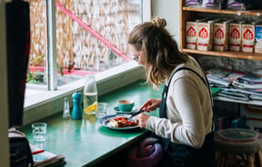 A woman eating at a counter by the window inside Gispy Kitchen cafe Wellington.