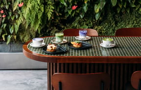 Wooden bar leaner with green tiles holding plates of sweet and savoury crumpets and ube and matcha lattes