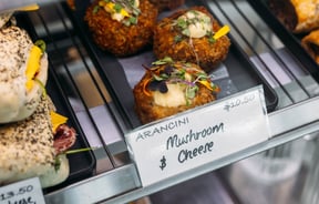 Close up of arancini on a tray inside a glass cabinet.