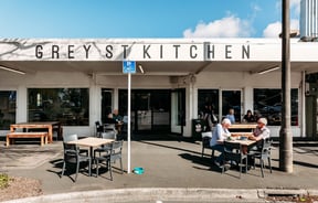 The exterior of Grey Street Kitchen with tables and chairs on the footpath in the sun.