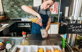 A woman mixes a drink behind the bar at Hayes Common, Hamilton.