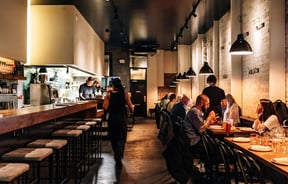 Long narrow restaurant with people dining in rows.