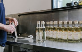 Bottles of gin lined up in a row waiting for stickers to be placed on them at Humdinger Gin Distillery in Geraldine.