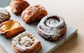 Pastries on a board on top of a wooden counter.
