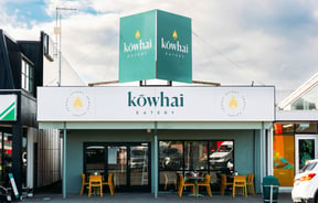 Cafe building exterior with bright green signage for Kōwhai Eatery.