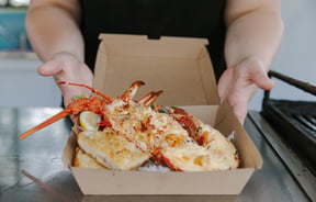 Takeaway box with cooked crayfish dish inside.