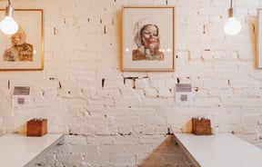 White tables against a painted-white brick wall.