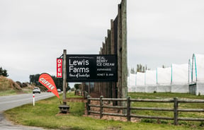Large black signage outside the farmland of Lewis Farms.