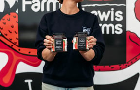 Staff member holding two jars of preserves at Lewis Farms.