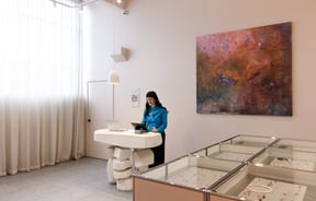 A woman in a blue shirt working inside Meadowlark Jewellery Auckland.