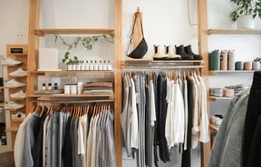 Clothes, shoes and bottles hung on wooden display racks and shelves.