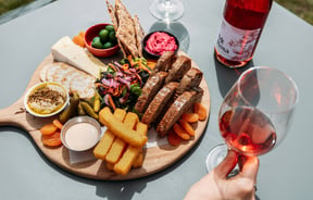 A cheese platter and a glass of rose wine.