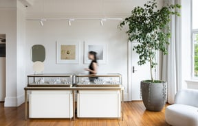 Wide shot of jewellery showroom with cabinet full of jewellery and a shop assistant behind at Naveya & Sloane Jewellery.