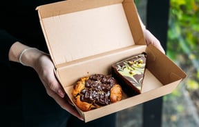 A cookie and slice in a box from Neverland Cakes.