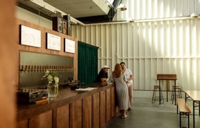 A man and woman chatting to a staff member at the counter at Norma Taps in Auckland.