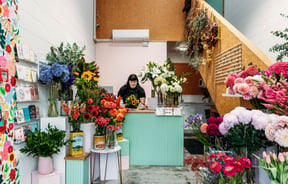 A woman behind a counter at a flower shop.