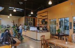 Wide view of the cafe space, customers at the counter and customers sitting at tables at Prima Roastery.