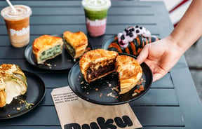 Someone placing steak and cheese pie down on table at Puku Pies in Petone
