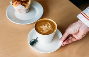 Waiter putting coffee and muffin down on cafe table