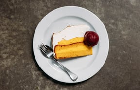 Close up of lemon meringue cake with a scoop of black Doris plum sorbet