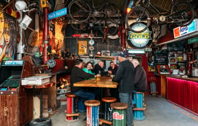 A group of men sitting around a high table in a pub.