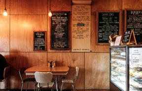 A set of table and chairs beneath the menu on the wall next to the food cabinet at Taper.
