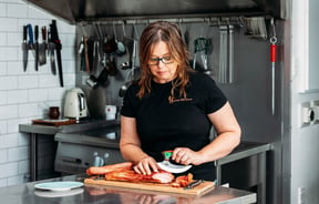 Owner Anna slicing sausages at The Polish Sausage Company in Lyall Bay Wellington
