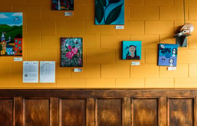 Small works of painted art on a painted wall.