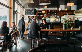 Customers sitting at tables inside a wooden decorated Raumati Social Club.