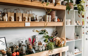 Flowers and candles on display on white shelves inside The Wilderness.