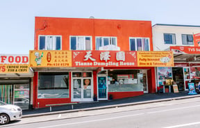 The bright orange exterior of a dumpling house on a sunny day.