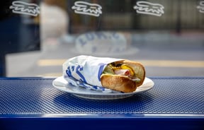 Close up of a sandwich on a blue bench.