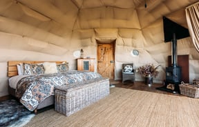 A bedroom set inside a Glamping pod with a wooden panelled floor.