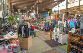 Main shop floor displaying second hand goods on racks and shelves at Wastebuster.