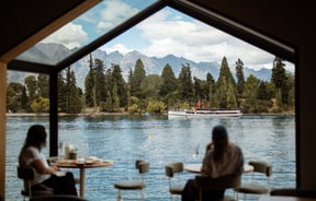 People sitting with a drink looking at view out window at Wharf Bar