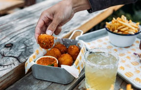 Hands holding a deep fried ball.