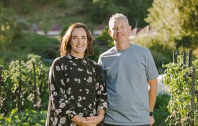 Hayley and Chris smiling at the camera from their garden.