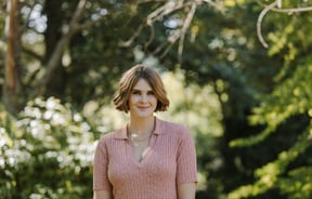 Jess smiling to camera wearing a pink dress.