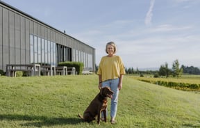 Pen and her dog standing in front of Black Estate on a sunny day.