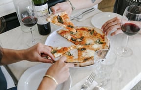 Diners enjoy a slice of pizza from one of the 10 best pizza spots in Christchurch.