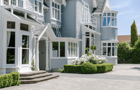 The exterior of Christchurch accommodation with roses and hedged in front.