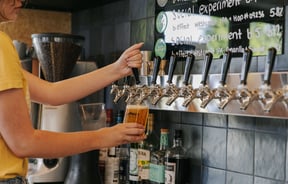A staff member pulling a pint of craft beer behind the counter at B.Effect in Wanaka.