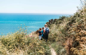 A group of people are walking on a track with the ocean in the background.