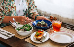 A woman sitting at a table with plates of food at Ombra Wellington.