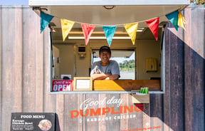 Food truck in a carpark with the road in the background.