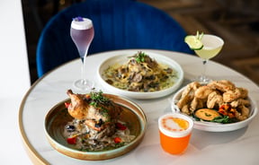 Plates of food and cocktails on a table.