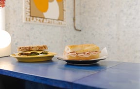 Two simple sandwiches placed next to each other on blue table at Odds in Christchurch