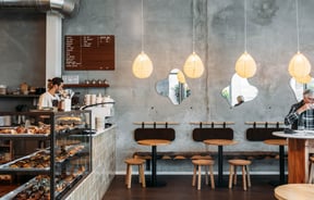 Barista behind counter and customer sitting at table at Crumb Bakehouse.