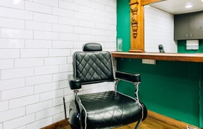 Black barber chair in front of salon mirror at Boar and Blade in Wellington