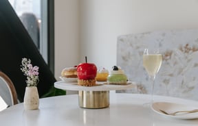 Shiny cakes on a cake stand on a white table.